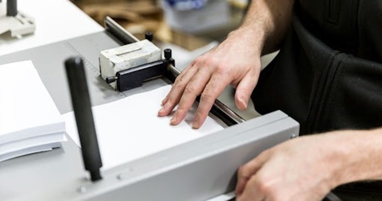 man cutting paper on machine